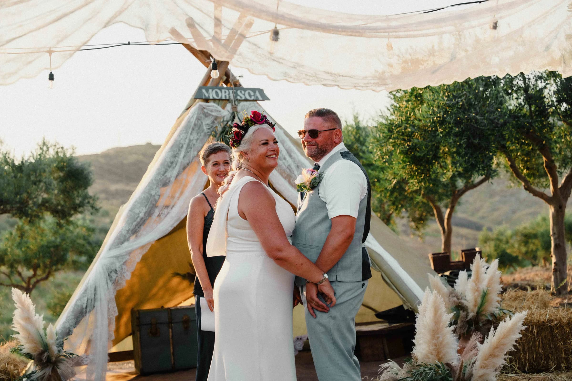 Cristiana Romano leading a ceremony at Moresca Farm at golden hour, beneath a linen tent among olive trees