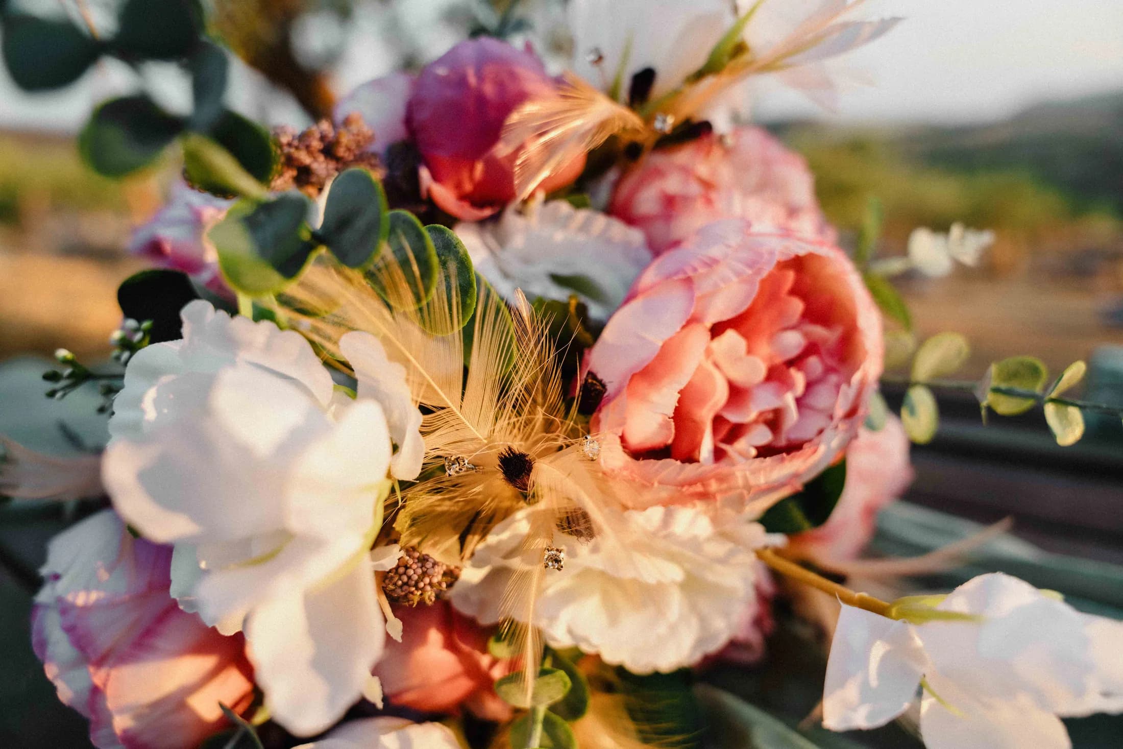 A bouquet of peonies and wildflowers against pampas grass