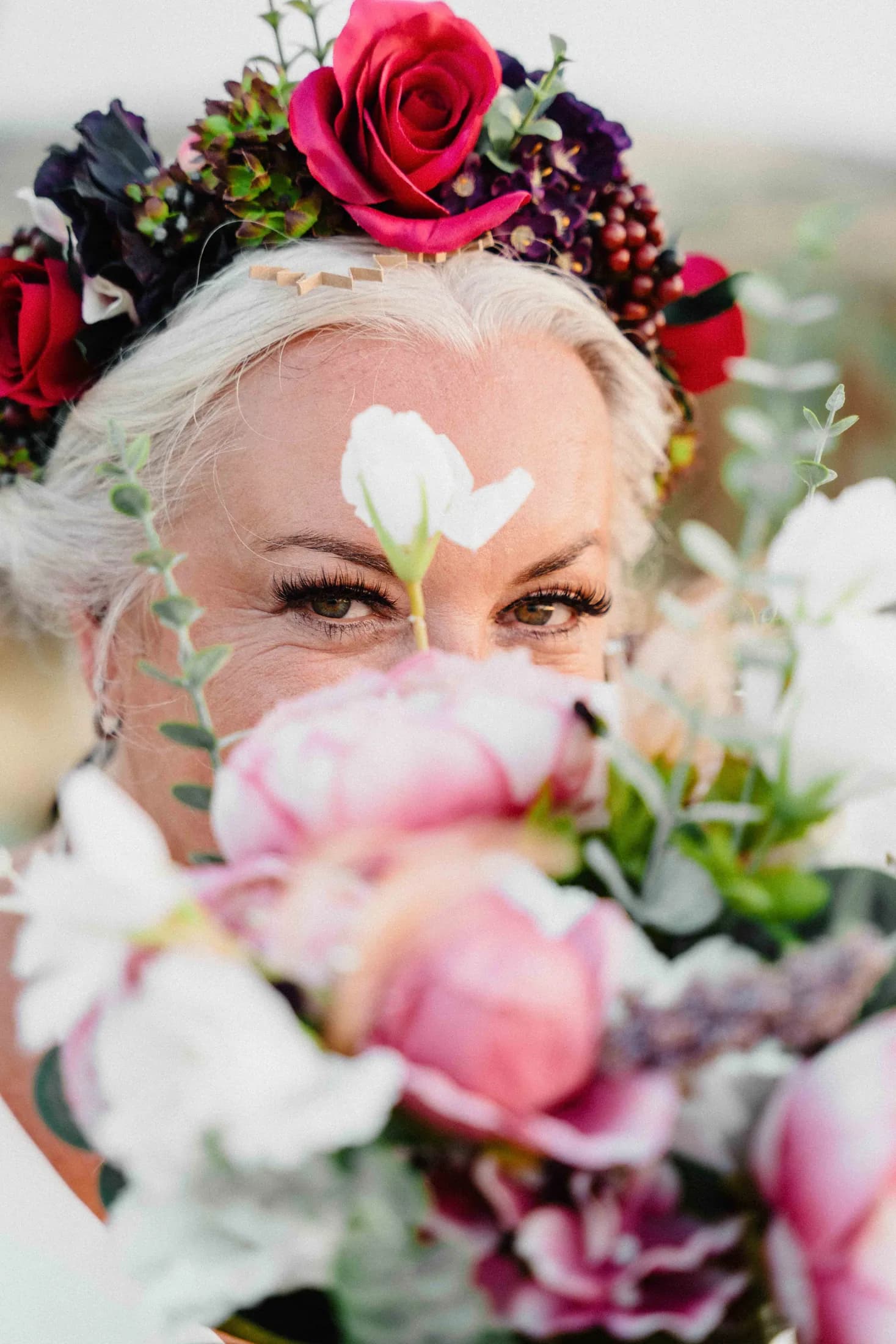 A bride in a flower crown, blooms held close to her face