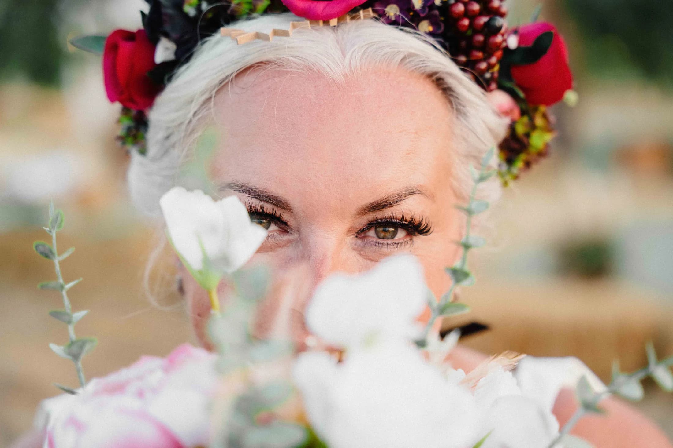 The bride's eyes above her bouquet, half-hidden by petals