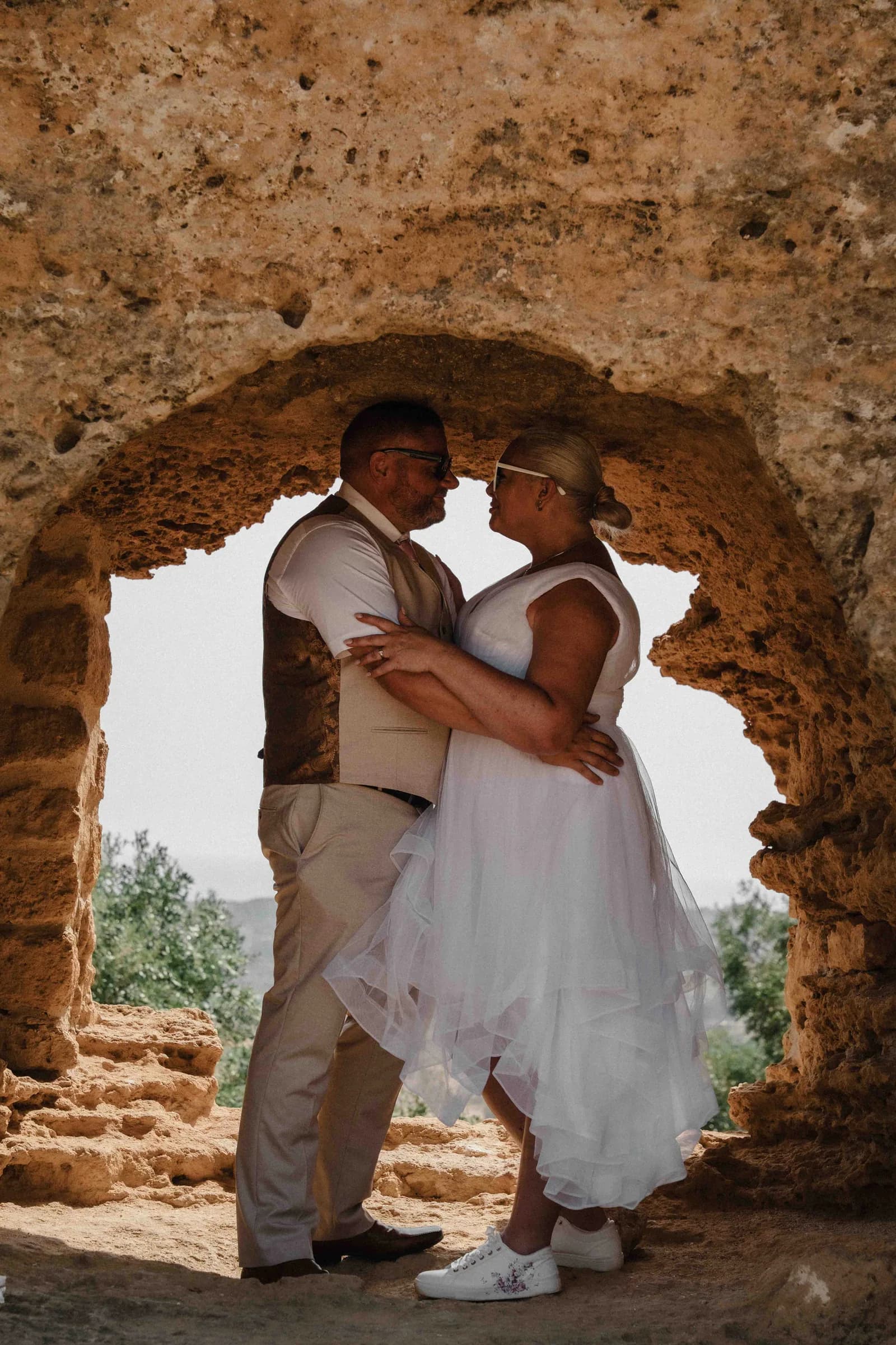 A couple embracing framed inside an arch cut in golden stone