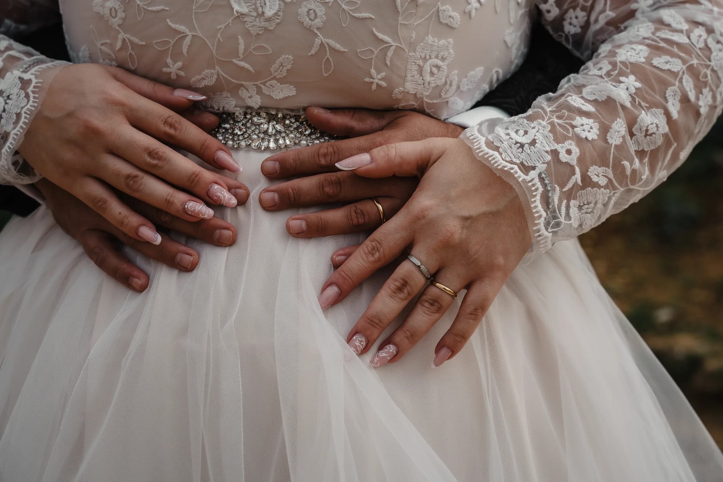 Hands resting on lace, both rings visible